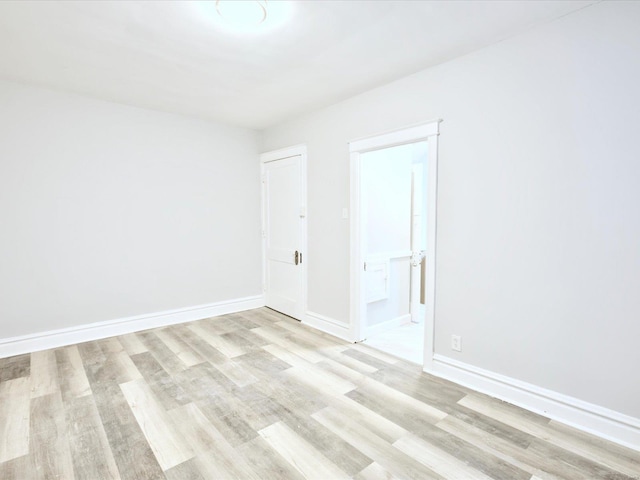 spare room featuring baseboards and light wood-style floors