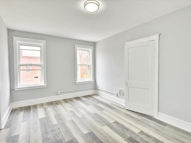 empty room featuring light wood-type flooring and baseboards