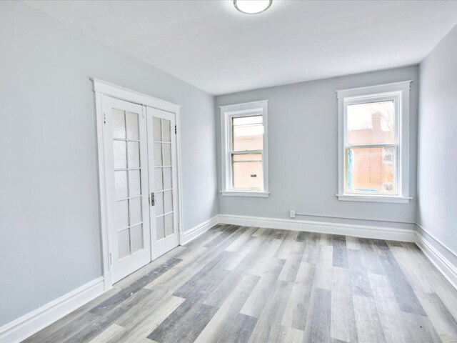 unfurnished room featuring french doors, baseboards, and wood finished floors