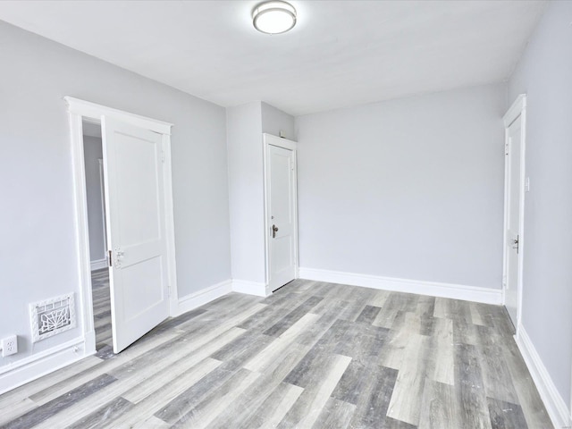 unfurnished bedroom featuring visible vents, baseboards, and wood finished floors