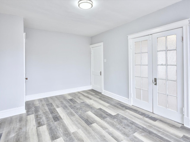 spare room with french doors, baseboards, and wood finished floors