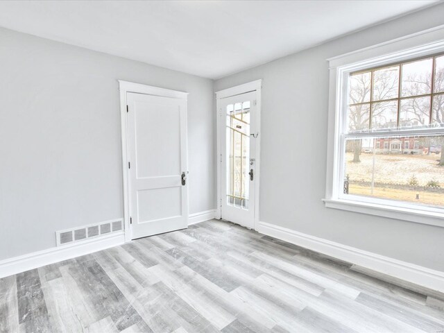 foyer entrance with wood finished floors, baseboards, and visible vents