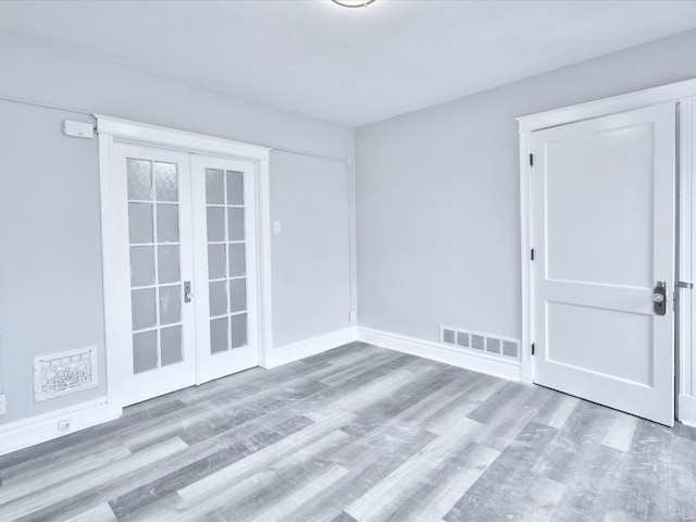 empty room with visible vents, baseboards, wood finished floors, and french doors