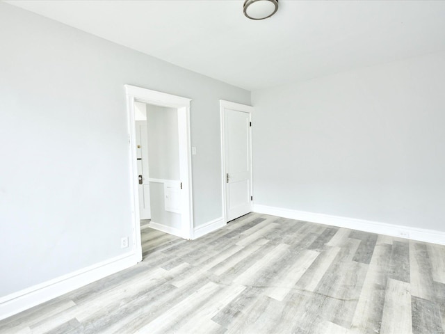 empty room featuring baseboards and light wood finished floors