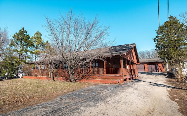 view of front facade featuring a shingled roof, a porch, a front yard, a garage, and driveway