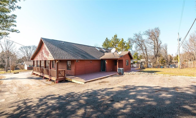 rear view of property with central AC unit, fence, roof with shingles, and a wooden deck