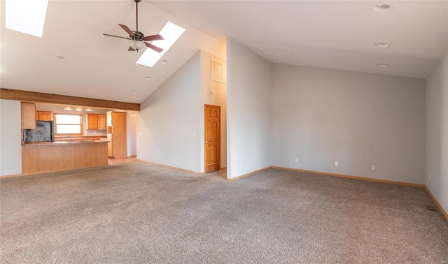 unfurnished living room with baseboards, high vaulted ceiling, a skylight, ceiling fan, and light colored carpet