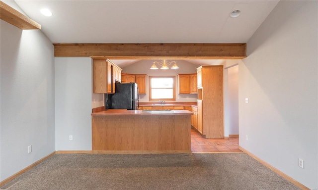 kitchen featuring a peninsula, vaulted ceiling with beams, freestanding refrigerator, a sink, and light carpet