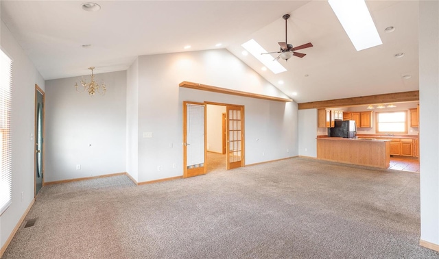 unfurnished living room featuring visible vents, light carpet, high vaulted ceiling, a skylight, and baseboards