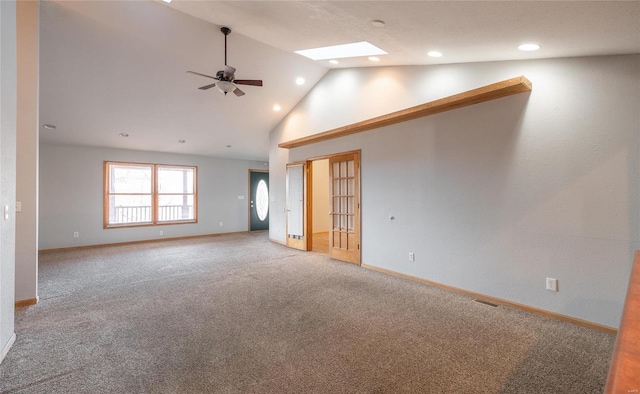 empty room featuring a ceiling fan, a skylight, carpet, and baseboards