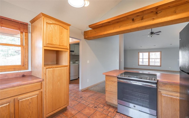 kitchen featuring washing machine and dryer, vaulted ceiling, light tile patterned floors, stainless steel range with electric stovetop, and a ceiling fan