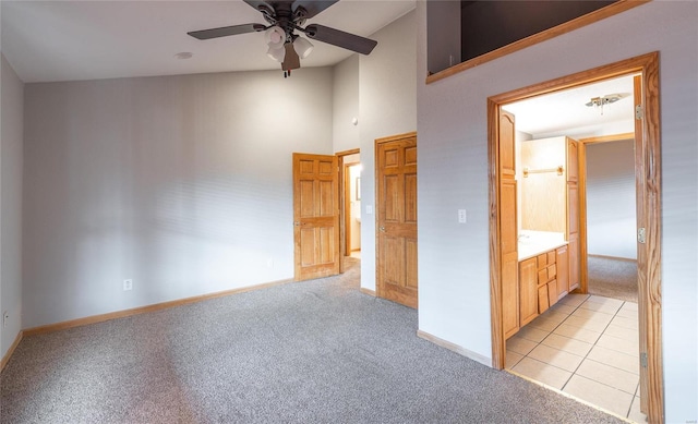 unfurnished bedroom featuring baseboards, light carpet, a towering ceiling, light tile patterned flooring, and a ceiling fan