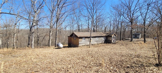 view of yard featuring a wooded view, a storage shed, and an outdoor structure