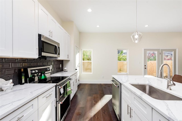 kitchen featuring dark wood finished floors, a sink, stainless steel appliances, white cabinetry, and backsplash