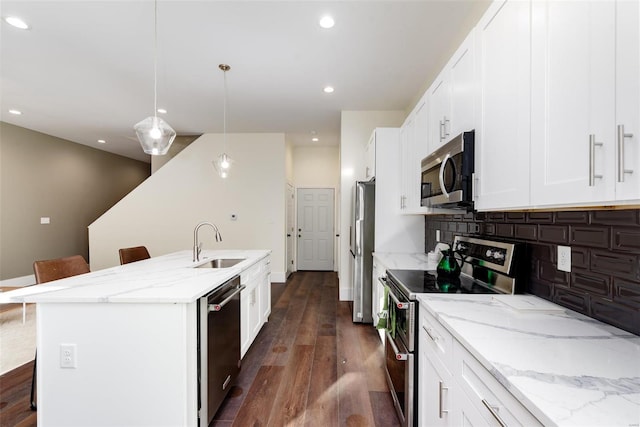 kitchen featuring tasteful backsplash, dark wood finished floors, a center island with sink, appliances with stainless steel finishes, and a sink