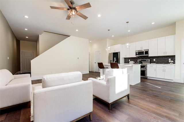 living room featuring recessed lighting, baseboards, a ceiling fan, and dark wood-style flooring