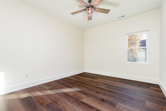 spare room featuring ceiling fan, visible vents, baseboards, and dark wood-style floors