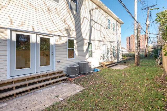 view of side of property featuring central AC unit, entry steps, a lawn, and fence