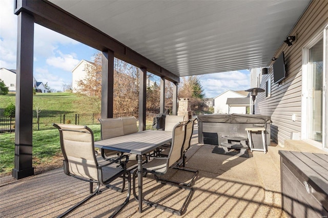 view of patio featuring outdoor dining space, fence, and a hot tub