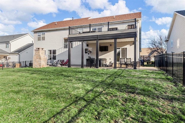 back of house with a lawn, a fenced backyard, a balcony, and a patio area