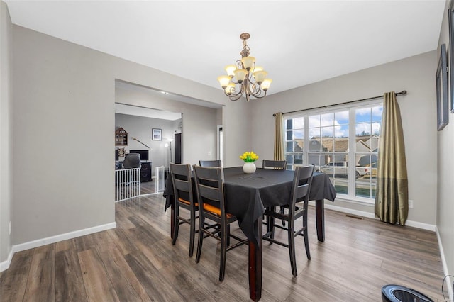 dining space with baseboards, wood finished floors, and a chandelier