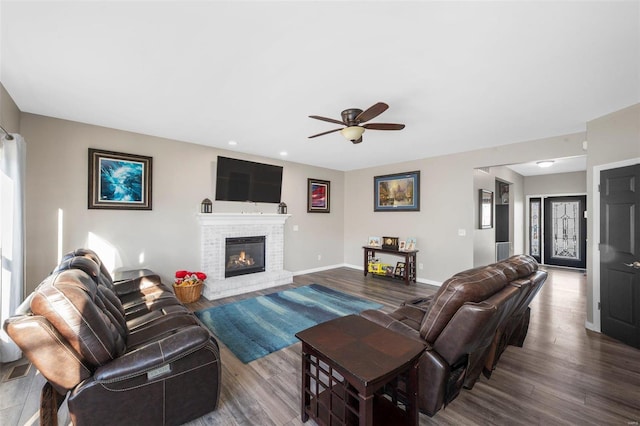 living area with dark wood finished floors, a fireplace, baseboards, and ceiling fan