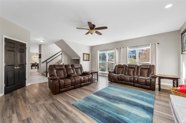 living room with ceiling fan with notable chandelier, wood finished floors, recessed lighting, stairway, and baseboards