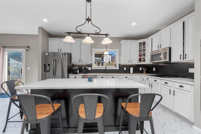 kitchen with tasteful backsplash, marble finish floor, appliances with stainless steel finishes, and a kitchen island