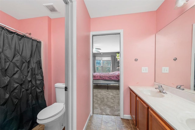 bathroom featuring visible vents, toilet, a sink, connected bathroom, and double vanity