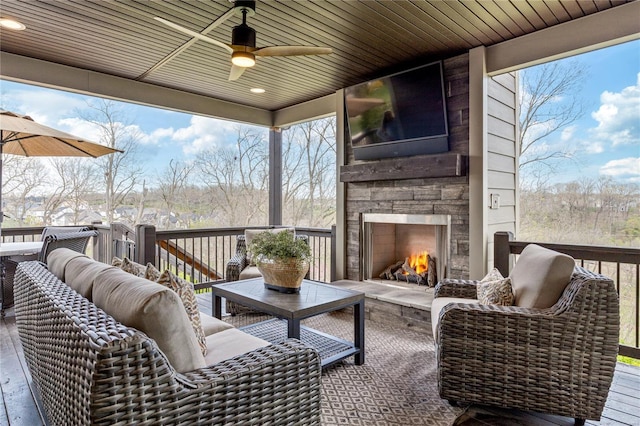 wooden deck featuring an outdoor living space with a fireplace and a ceiling fan