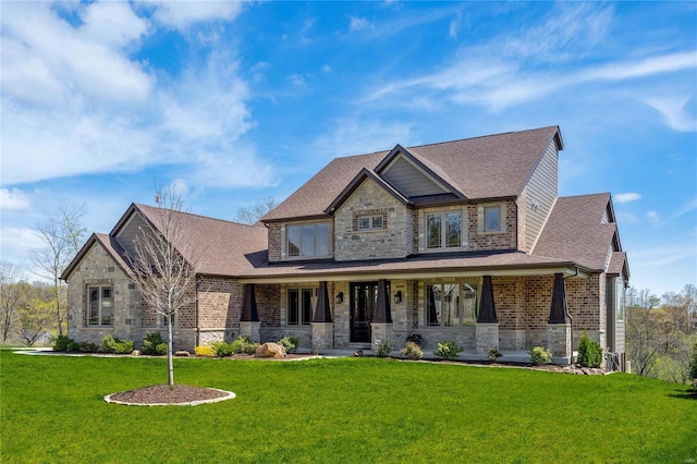 craftsman-style house featuring covered porch, a front yard, a shingled roof, and stone siding
