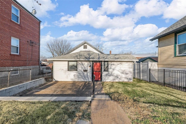 view of front facade featuring a shingled roof, a front lawn, a fenced backyard, and a patio