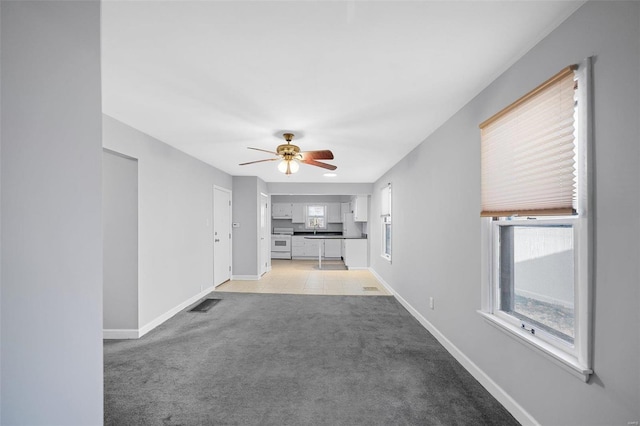 unfurnished living room featuring plenty of natural light, light colored carpet, visible vents, and baseboards