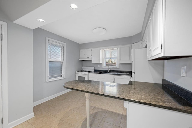 kitchen featuring a sink, white appliances, a peninsula, and white cabinetry