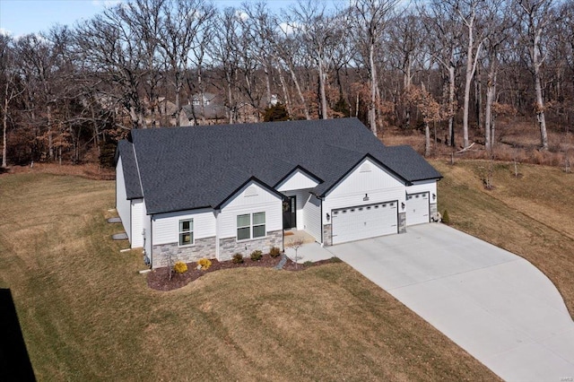 modern farmhouse style home with stone siding, a front yard, board and batten siding, and an attached garage