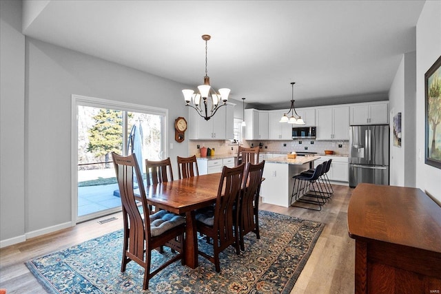 dining area featuring visible vents, baseboards, wood finished floors, and a chandelier