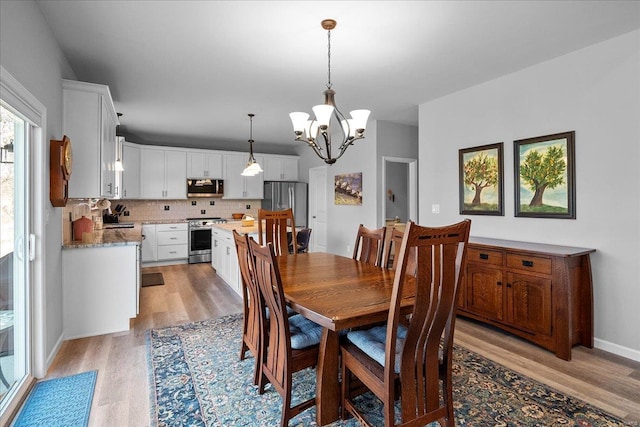 dining area featuring light wood finished floors, baseboards, and an inviting chandelier