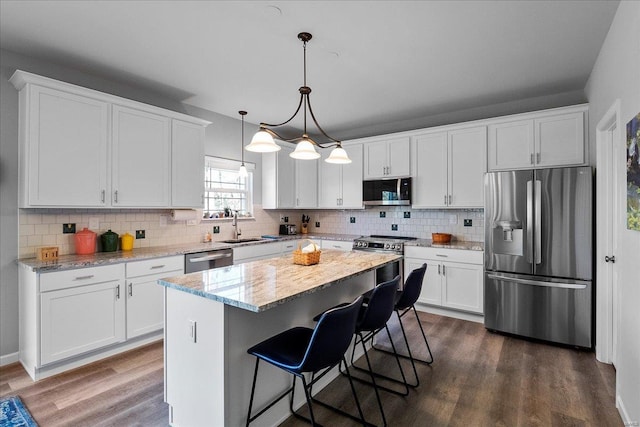 kitchen featuring backsplash, appliances with stainless steel finishes, dark wood-style floors, white cabinetry, and a sink