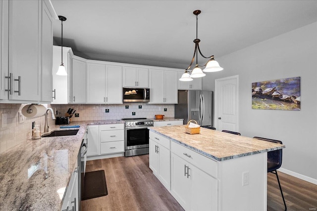 kitchen with tasteful backsplash, a kitchen island, dark wood finished floors, stainless steel appliances, and a sink