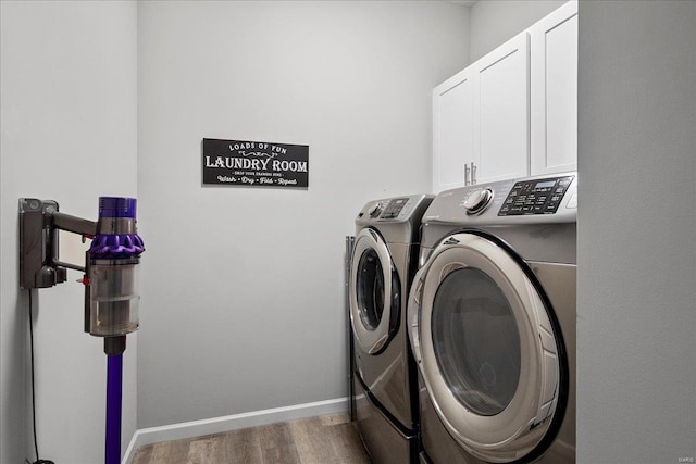 laundry area with wood finished floors, cabinet space, baseboards, and washing machine and clothes dryer