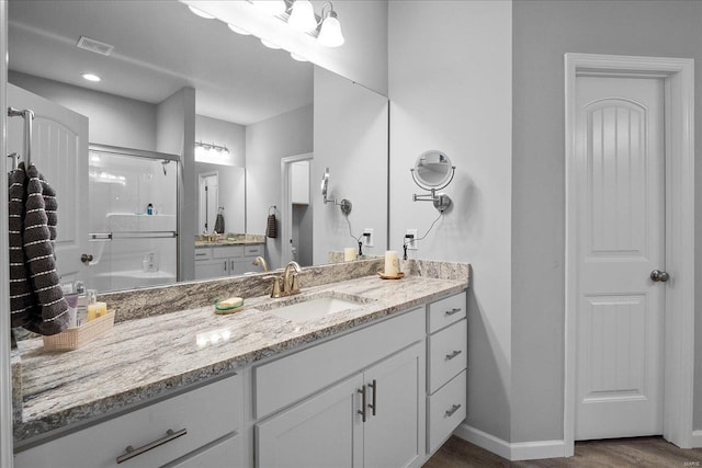 bathroom with vanity, wood finished floors, visible vents, and baseboards