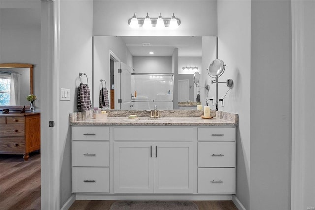 bathroom featuring vanity, wood finished floors, a shower, and baseboards