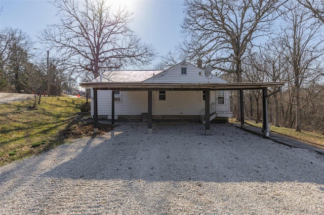 exterior space with driveway, an attached carport, and a chimney