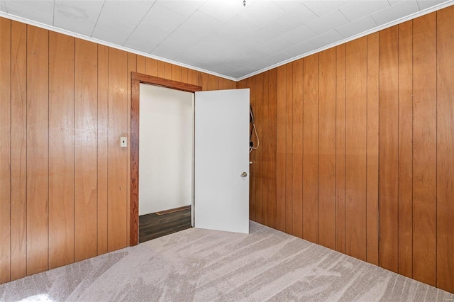 unfurnished bedroom with a closet, wooden walls, and carpet floors