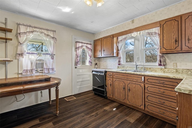 kitchen featuring light countertops, range, brown cabinets, and a sink