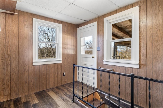 stairway with wood walls, a paneled ceiling, and wood finished floors