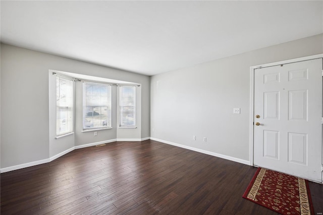 unfurnished room featuring baseboards and dark wood-style flooring