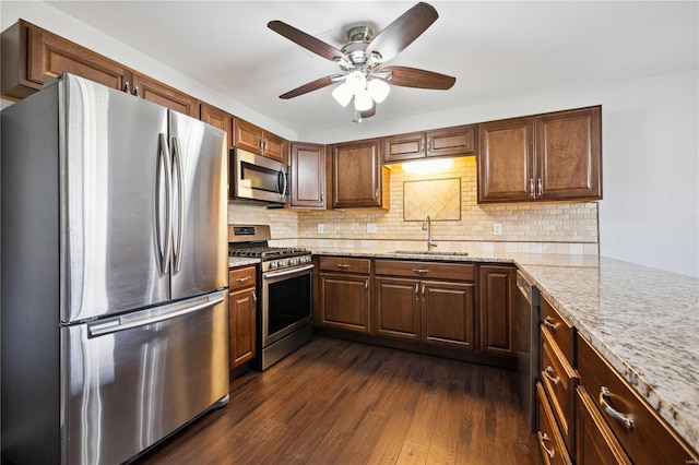 kitchen with a sink, dark wood-type flooring, backsplash, and stainless steel appliances