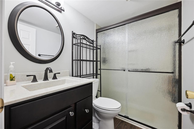 bathroom with vanity, a shower stall, toilet, and wood finished floors