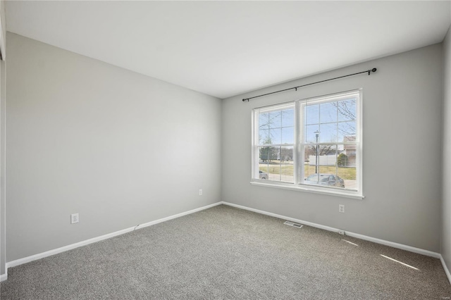 carpeted spare room with visible vents and baseboards